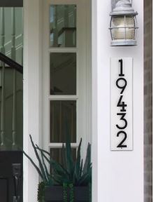 Floating house number sign against white exterior modern house